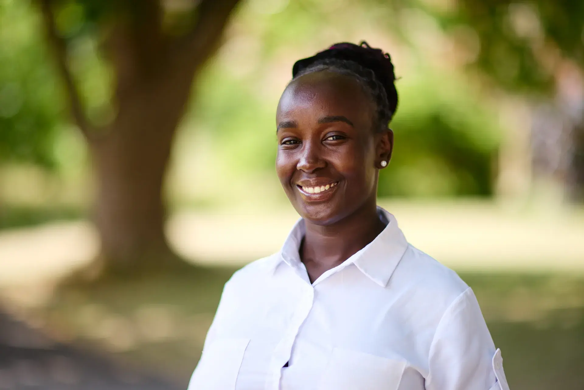 Outdoor portrait of Ruth Nanjala smiling in a white shirt